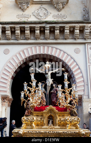 Jesus Christ on the Cross with Virgin Mary and Mary Magdalene on a gilded platform in procession during Holy Week in Cordoba. Stock Photo