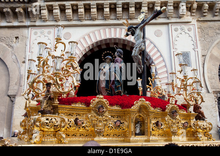 Jesus Christ on the Cross with Virgin Mary and Mary Magdalene on a gilded platform in procession during Holy Week in Cordoba. Stock Photo