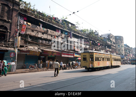 Yellow Kolkata tram passing Kolkata slums in the early morning, Kolkata, West Bengal, India, Asia Stock Photo