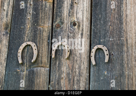 retro rusty horse shoes hang on nails in old wooden rural house wall. Stock Photo