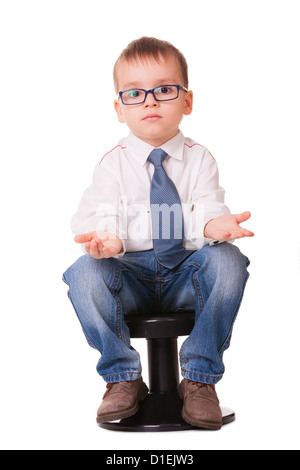 Confused clever kid in jeans and shirt sitting on small chair isolated on white background Stock Photo