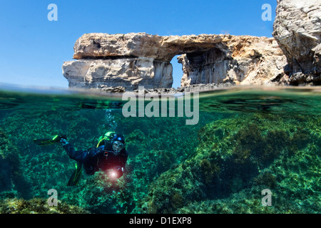 Split shot half and half with diver and rock arch Azure window in the Mediterranean Sea near Gozo, Malta Stock Photo