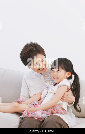 Grandmother and granddaughter smiling on the sofa Stock Photo