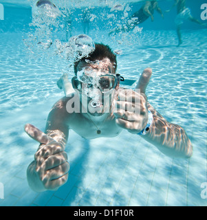 man floats underwater in pool Stock Photo