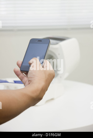 Hand holding a smartphone and an automated sphygmomanometer Stock Photo