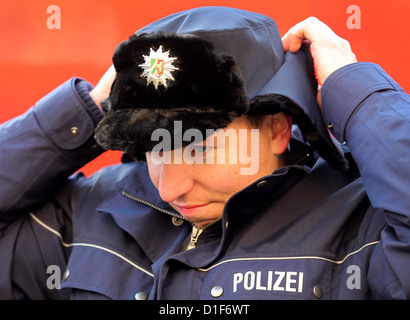 (dpa FILE) - An archive picture, dated 30 November 2011, shows police officer Marco Spelleken putting on a winter cap in Duesseldorf, Germany. The supply of police standard issued winter caps to police officers was discontinued due to a lack of quality and faulty manufacturing. Photo: Roland Weihrauch Stock Photo