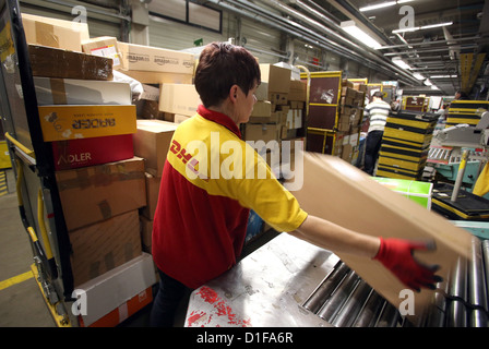 Karin Simon puts packages on the conveyor belt at the parcel sorting center of Deutsche Post DHL in Neustrelitz, Germany, 17 December 2012. Up to 20,000 parcels are sorted in an hour. Since November, the traffic doubled, and six million packages are sorted in total. Nationwide, Deutsche Post DHL expects a record in the number of packages delivered in the Christmas period. Photo: Bernd Wüstneck Stock Photo