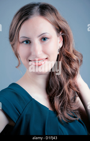 Studio portrait of a beautiful 20 year old redhead woman against blue background. Stock Photo