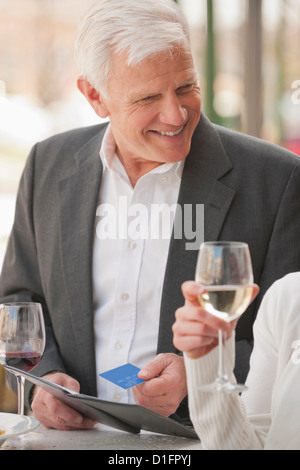Caucasian couple drinking wine and paying bill Stock Photo