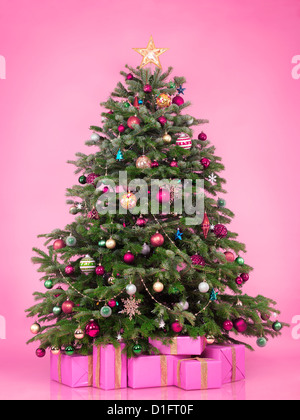 Decorated Christmas tree with presents and gift boxes isolated on pink background Stock Photo
