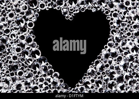 Hundreds of imitation diamonds on a black background with a heart shaped space in the middle. Stock Photo
