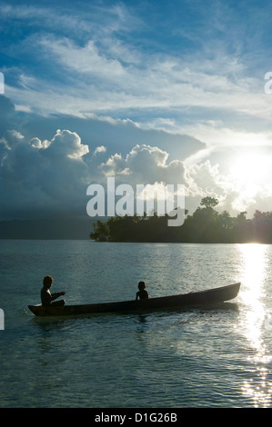 Boys in a canoe in backlit in the Marovo Lagoon, Solomon Islands, Pacific Stock Photo