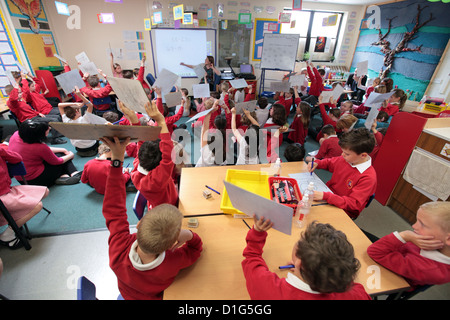 Primary junior school Mathematics Maths class, hands up with the answers, UK. Stock Photo