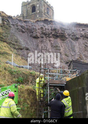 Contractors working urgently to stabilise steep slope below St Mary's church at Whitby.  Heavy rain risks causing a landslip endangering Houses and Fortunes famous Kipper smokery  in Henrietta Street in Whitby North Yorkshire UK.   Properties below have been evacuated as a precaution Stock Photo