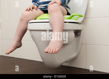 Young boy, 2 years old, sitting on a children's seat on a toilet. Stock Photo