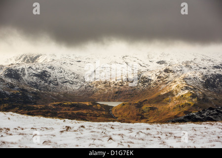 Looking through to Easdale Tarn from Fairfield in misty weather with drifting snow in high winds, Lake District, UK. Stock Photo