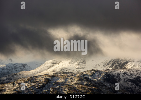 Looking through to the Langdale Pikes from Fairfield in misty weather with drifting snow in high winds, Lake District, UK. Stock Photo