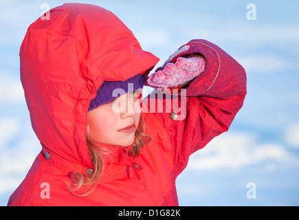 little ruddy nice girl in winter outwear with hood looks into the distance Stock Photo