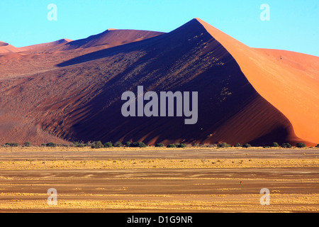 Two tourists dwarfed by a vast sand dune in the Namib Naukluft Park Stock Photo