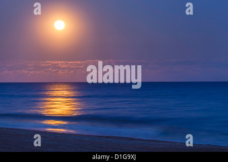 A full moon rises over the Atlantic Ocean and the beach of Emerald Isle in North Carolina. Stock Photo