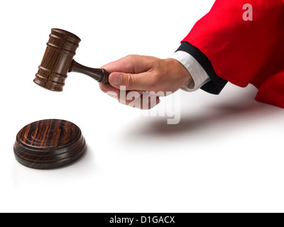 Law court judge's hand wearing red gown sleeve banging a gavel down onto a wooden disc Stock Photo