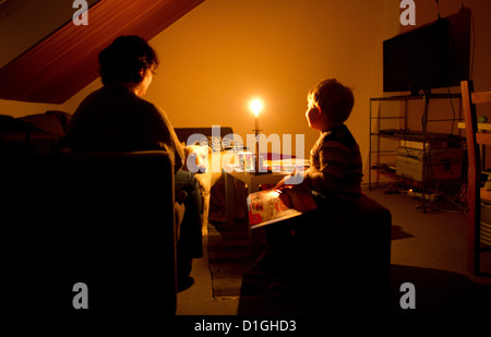 (ILLUSTRATION) An illustration dated 13 December 2012 shows a mother sits with her son in their dark home in Hanover, Germany. The room is lit by a candle. In November, the family went two and a half weeks without electricity after the municipal works turned off their power because of unpaid bills. Photo: JULIAN STRATENSCHULTE Stock Photo