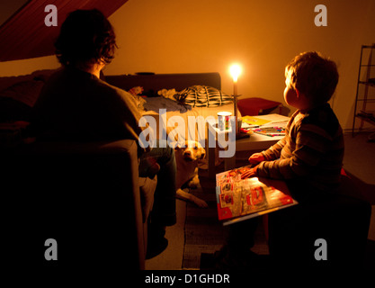 (ILLUSTRATION) An illustration dated 13 December 2012 shows a mother sits with her son in their dark home in Hanover, Germany. The room is lit by a candle. In November, the family went two and a half weeks without electricity after the municipal works turned off their power because of unpaid bills. Photo: JULIAN STRATENSCHULTE Stock Photo