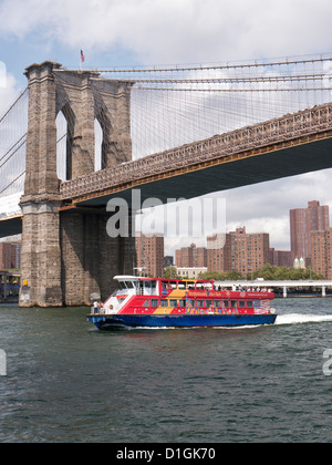 Sightseeing tourist boat steers under the Brooklyn Bridge Manhattan, New York City United States of America