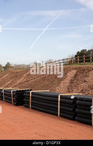 Stockpile of delivery of corrugated black  plastic twin wall sewer drainage pipes on new road building  site uk Stock Photo