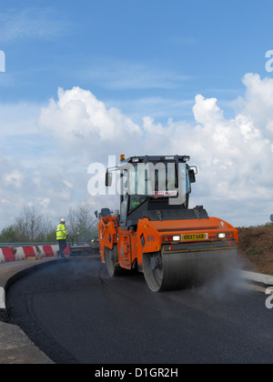 A Civil Engineering contractor highway maintenance gang  laying asphalt road surfacing in UK vibrating roller rolling Stock Photo