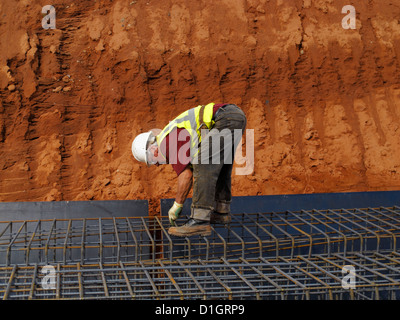Steel fixer tying reinforcement bars in a bridge foundation base construction building site worker workers UK Stock Photo