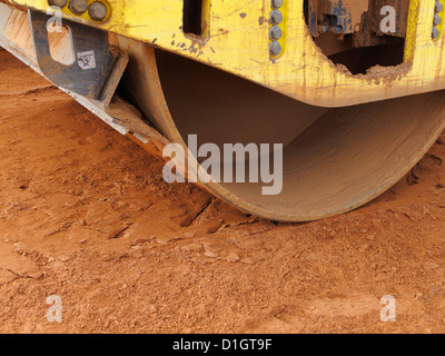 Detail wheel scraper of vibrating road roller on red soil UK Stock Photo