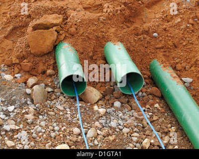 Road construction site UK trench with green ducts for cable TV and internet fibre-optic fiber optic communication cables Stock Photo