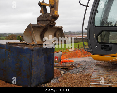 Digger bucket resting on a tank of diesel fuel to prevent theft on a UK road construction site. Stock Photo