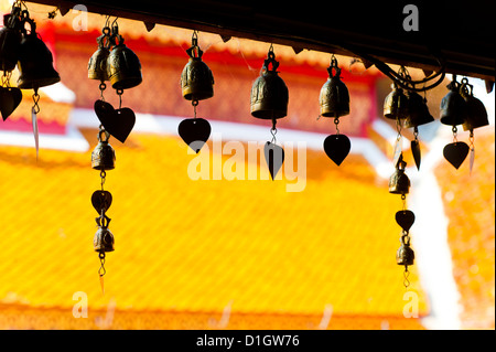 Close up of prayer bells, silhouetted against the colourful roof at Wat Doi Suthep, Chiang Mai, Thailand, Southeast Asia, Asia Stock Photo