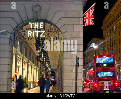 The Ritz Hotel at Christmas with Union Jack flag shoppers and passing red London bus Piccadilly London Stock Photo