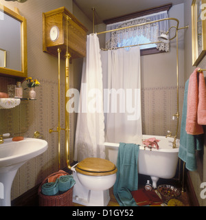 BATHROOMS Victorian bathroom with footed tub and pull flush toilet brass shower curtain rod  lace curtains wallpaper peach and Stock Photo