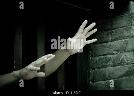 Prisoner hands stretch out from prison bars Stock Photo