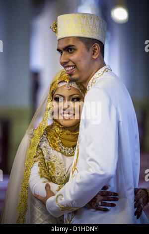 Dec. 22, 2012 - Singapore, Singapore - A bride and groom pose for guests' photos at the Sultan Mosque in Singapore. The Sultan Mosque is the focal point of the historic Kampong Glam area of Singapore. Also known as Masjid Sultan, it was named for Sultan Hussein Shah. The mosque was originally built in the 1820s. The original structure was demolished in 1924 to make way for the current building, which was completed in 1928. The mosque holds great significance for the Muslim community, and is considered the national mosque of Singapore. It was designated a national monument in 1975. (Credit Imag Stock Photo