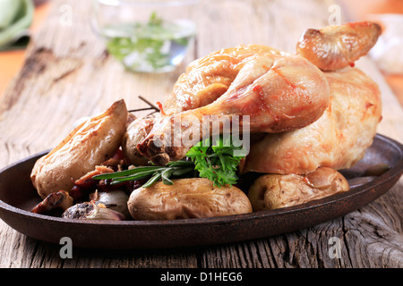 Roast chicken and potatoes on cast iron platter Stock Photo