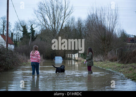 Near Black Notley, Essex, a BMW SUV is abandoned in flood water on a rural road. Recent rainfall has lead to saturated ground with no where for the water to seep away. Two girls walking their dog stop to look at the car. Stock Photo