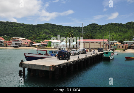 Blue sky sea view, to green interior hills, boats moored, taxis standing ferry pier, Hillsborough, Carriacou, West Indies Stock Photo