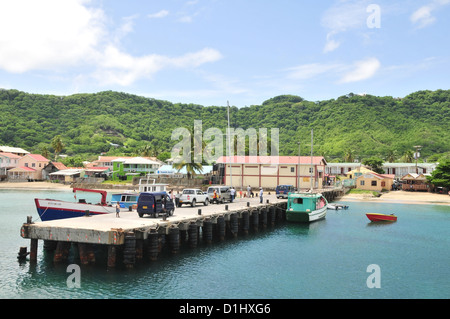 Blue sky white clouds sea view, to green interior hills, people taxis standing ferry  pier, Hillsborough, Carriacou, West Indies Stock Photo