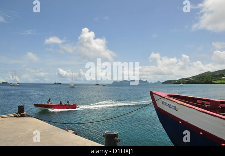 Blue sky view, to Union Island, red boat moving sea, blue fishing boat moored pier, Hillsborough, Carriacou, West Indies Stock Photo