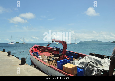 Blue sky seascape, to Union Island, small cargo boat with boxes crates crane, moored pier, Hillsborough, Carriacou, West Indies Stock Photo