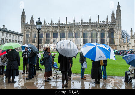 Kings College Cambridge UK  24th December 2012. Crowds queue in pouring rain for tickets for the Festival of Nine Lessons and Carols held in the famous chapel on Christmas Eve. Some people camped overnight and others arrived at 4.30am to secure a place in the queue.  The concert is broadcast across the world. The weather did not dampen people's spirits. Stock Photo