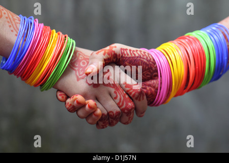 Shaking hands decorated with colorful bracelets Stock Photo