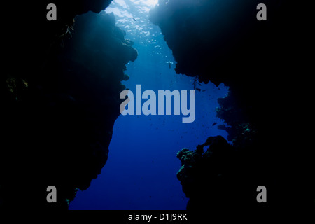 Sunrays filter down through the exit of a shallow water sea cave Stock Photo