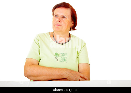 pensive senior woman sitting on a table Stock Photo