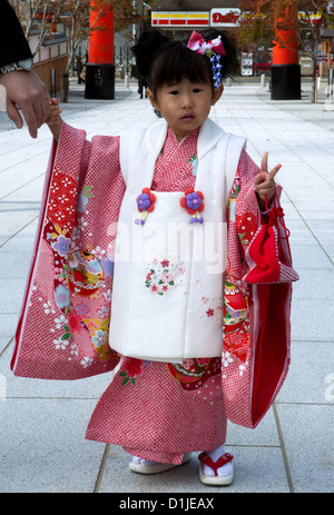 Small Japanese girl dressed in traditional kimono to visit the Fushimi Inari Temple for the Shichi-Go-San (Seven-Five-Three) festival Stock Photo